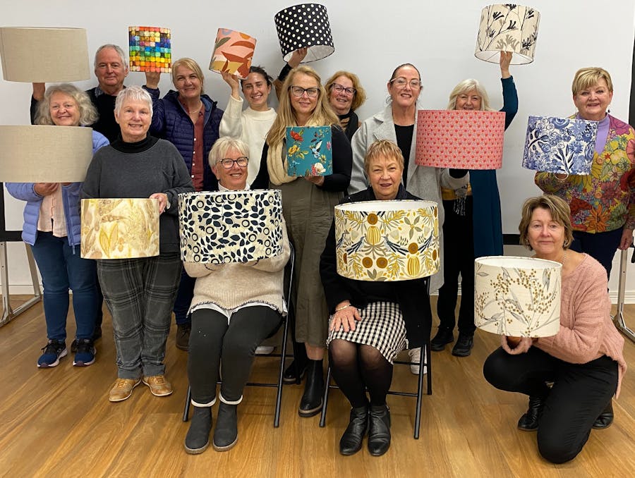 group of people holding lampshades they have just made in workshop