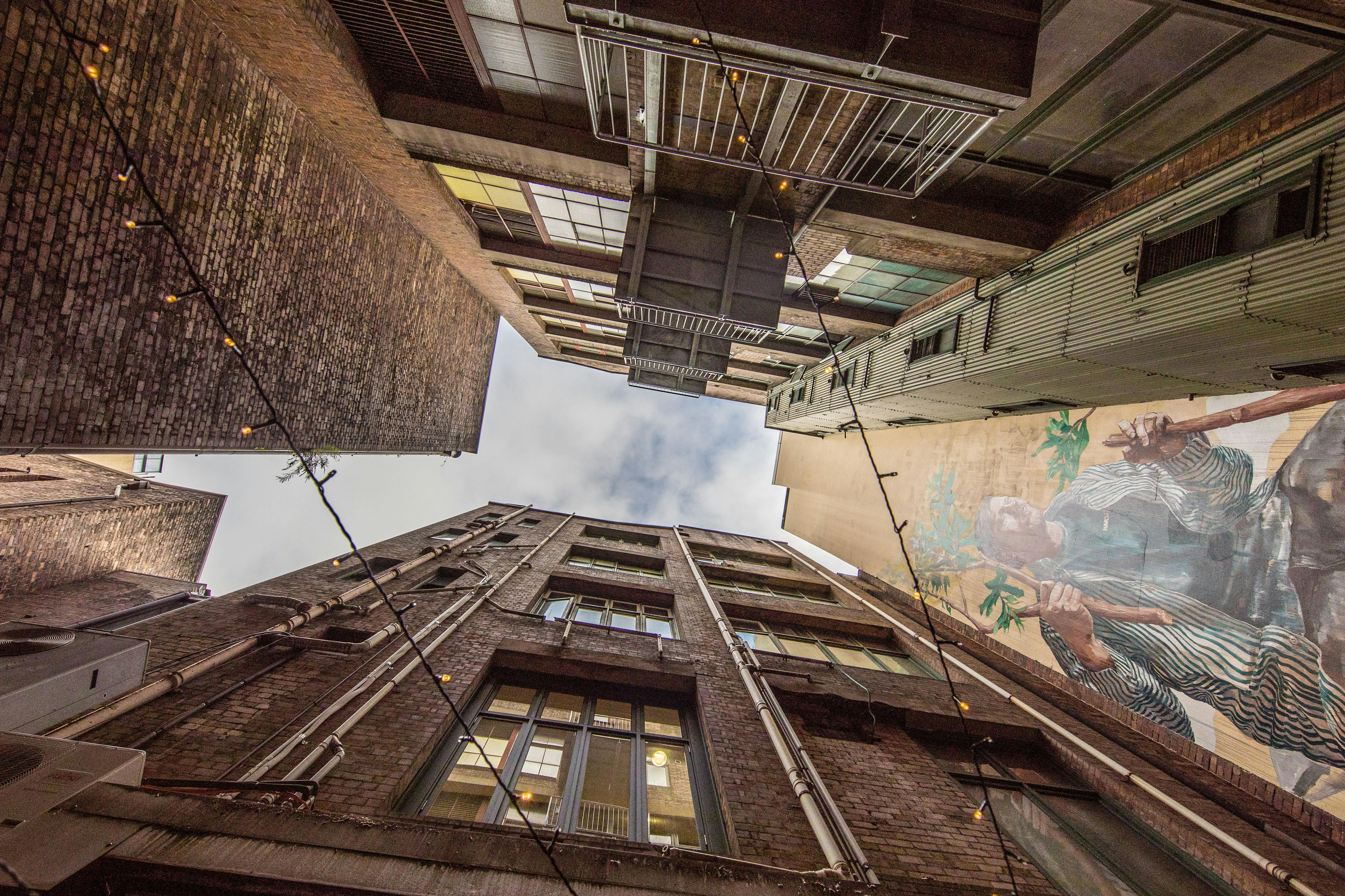 從庭院望向天空，兩側是高聳的五層建築，還有一幅壁畫。