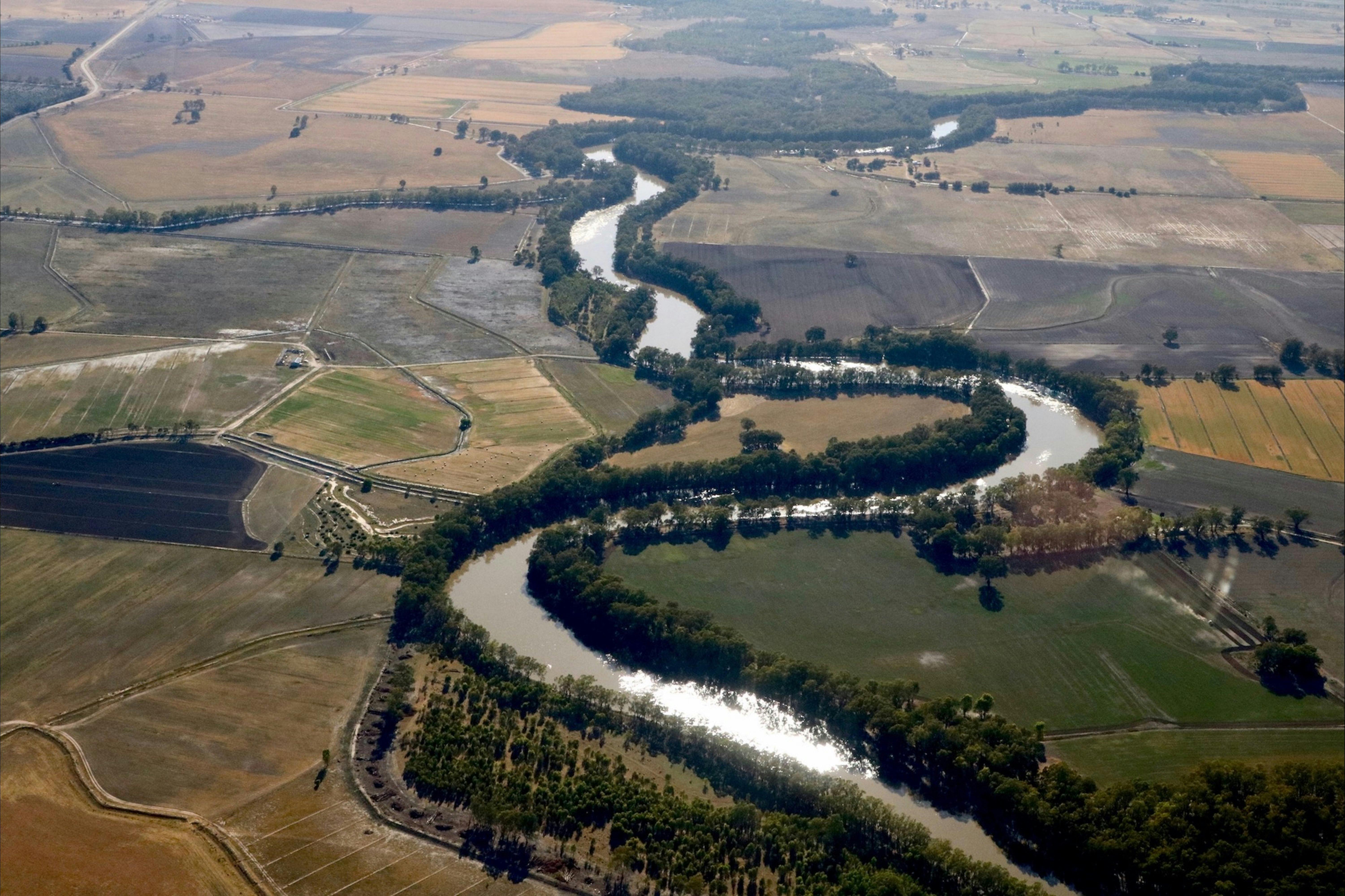 Aerial view showing winding river glinting in sunshine.