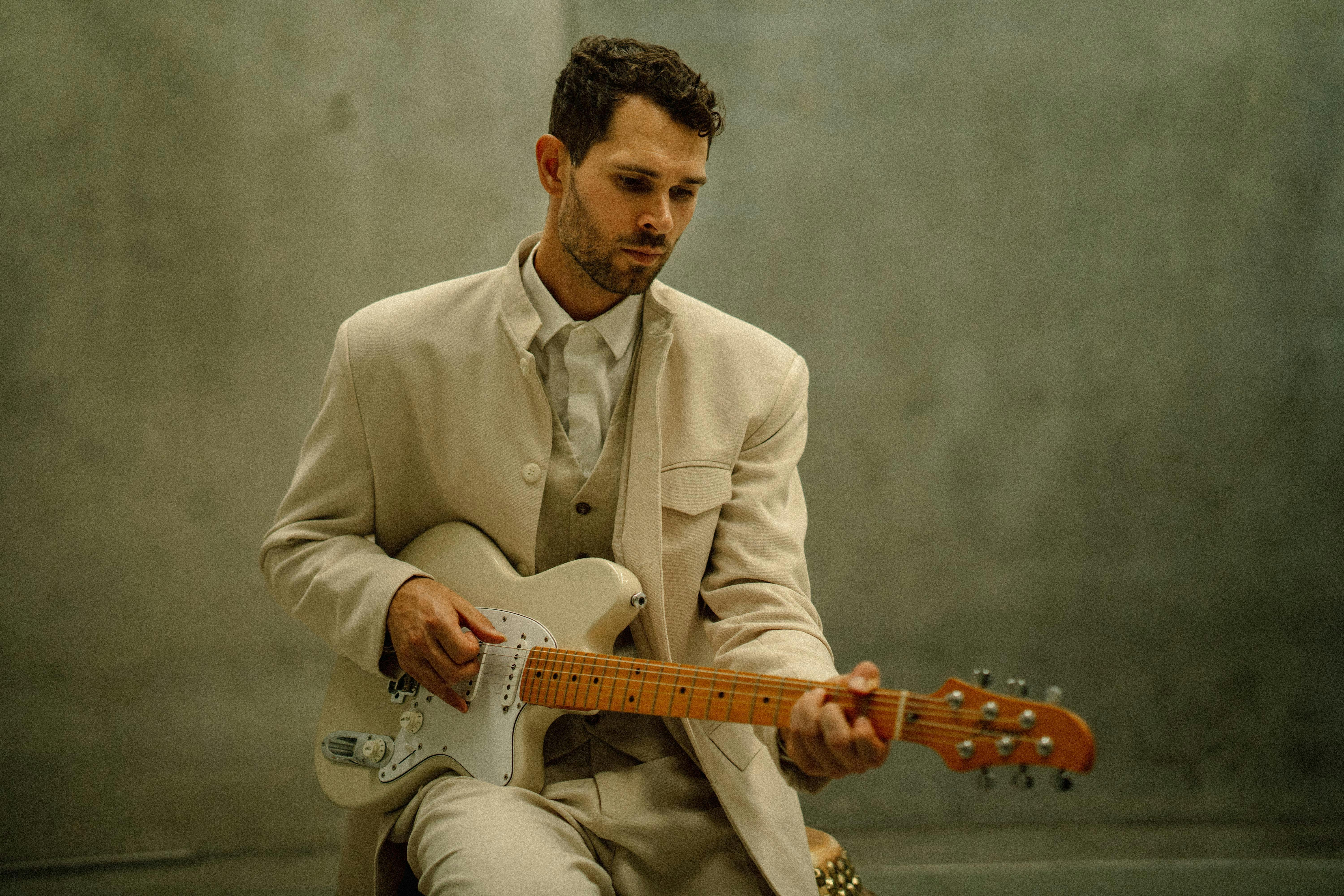 Ernest Aines in cream suit sitting holding guita