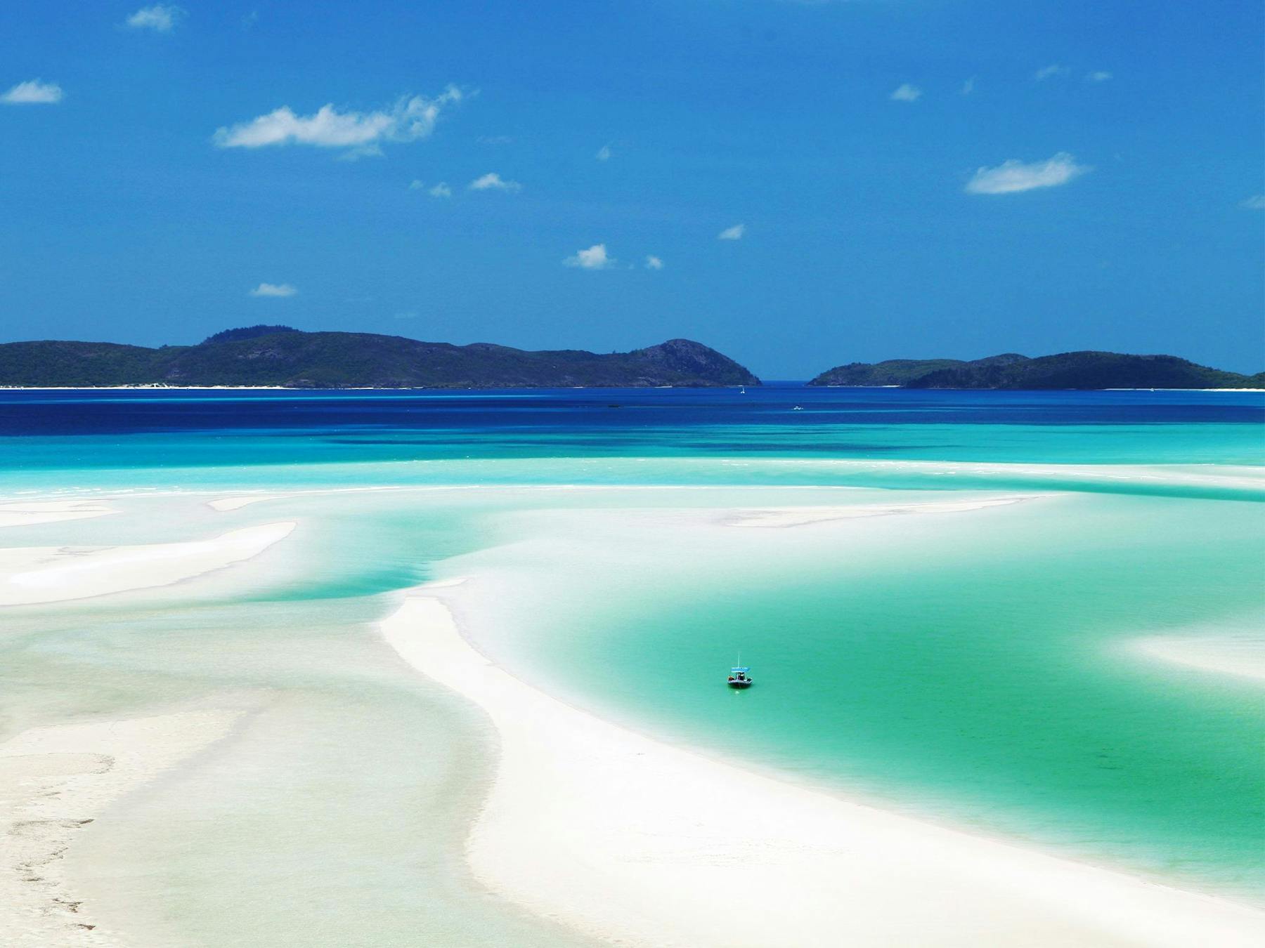 Looking out over white sand and turquoise water to islands in the distance.