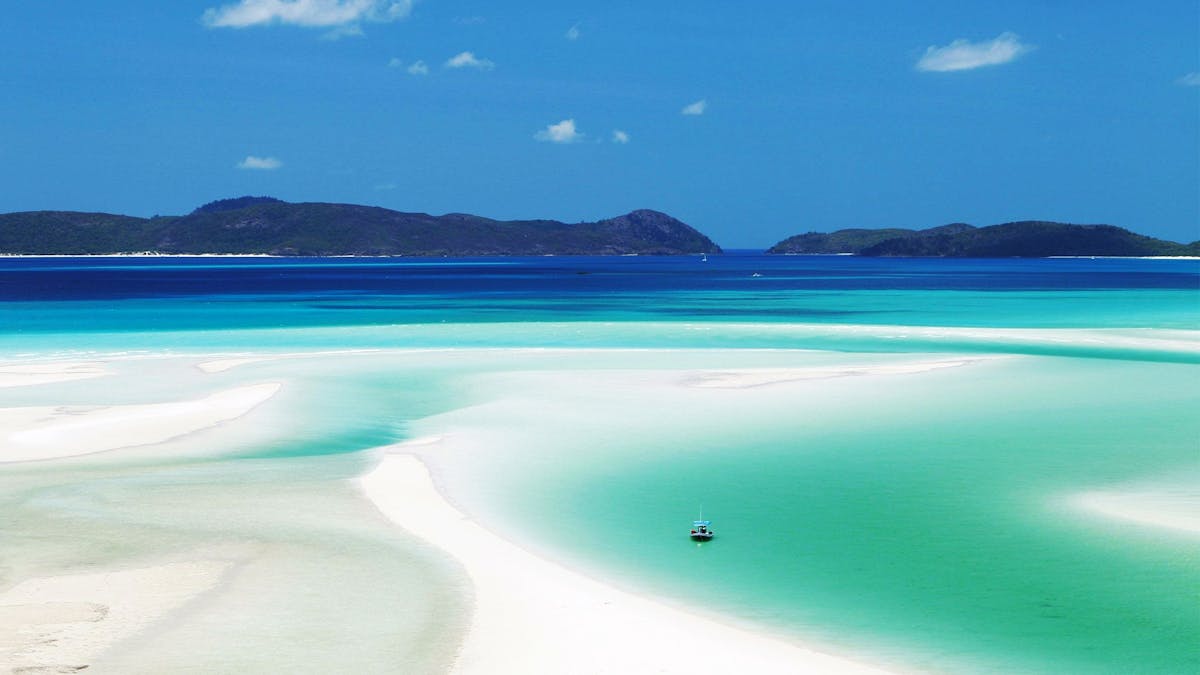 Looking out over white sand and turquoise water to islands in the distance.