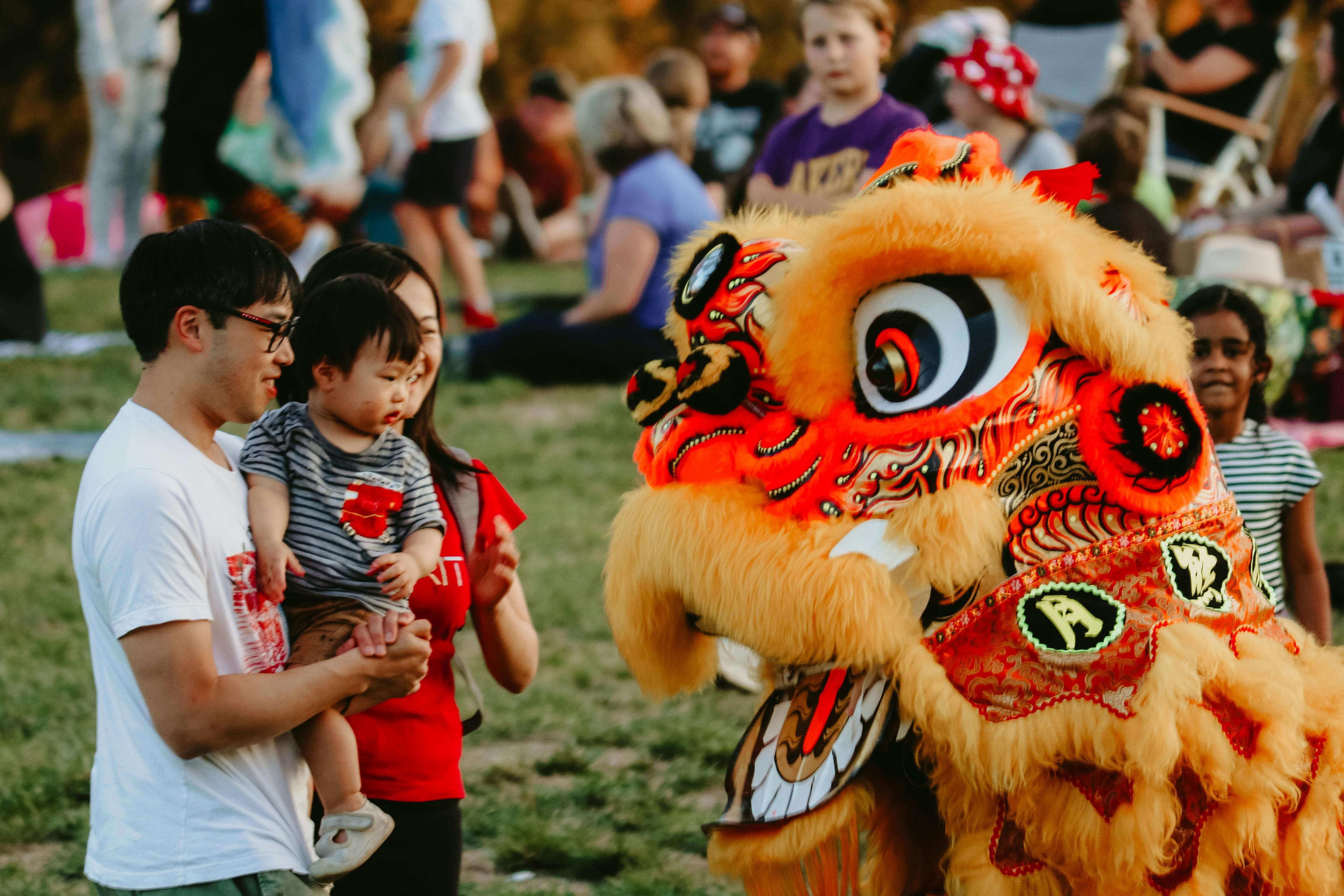 Image of a dragon dancer greeting a man and baby