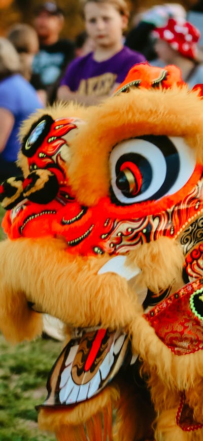 Image of a dragon dancer greeting a man and baby