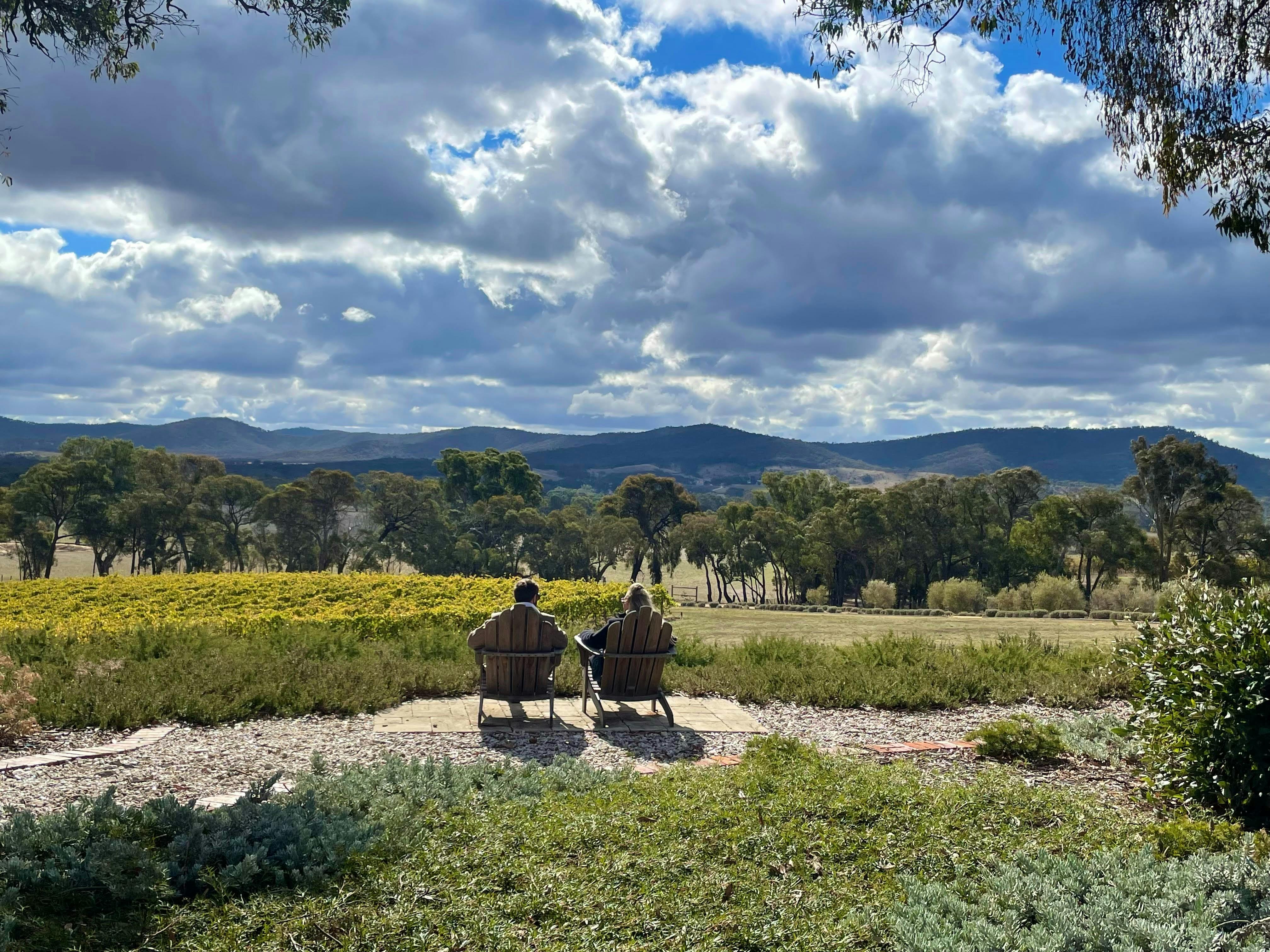 A couple seated outdoors at Bigibila Wines taking in the stunning views on a Silver Mink Tour