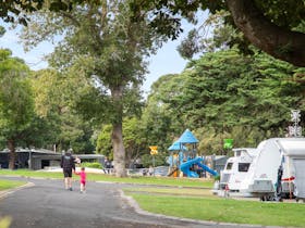 A parent and child walking past caravans towards a playground