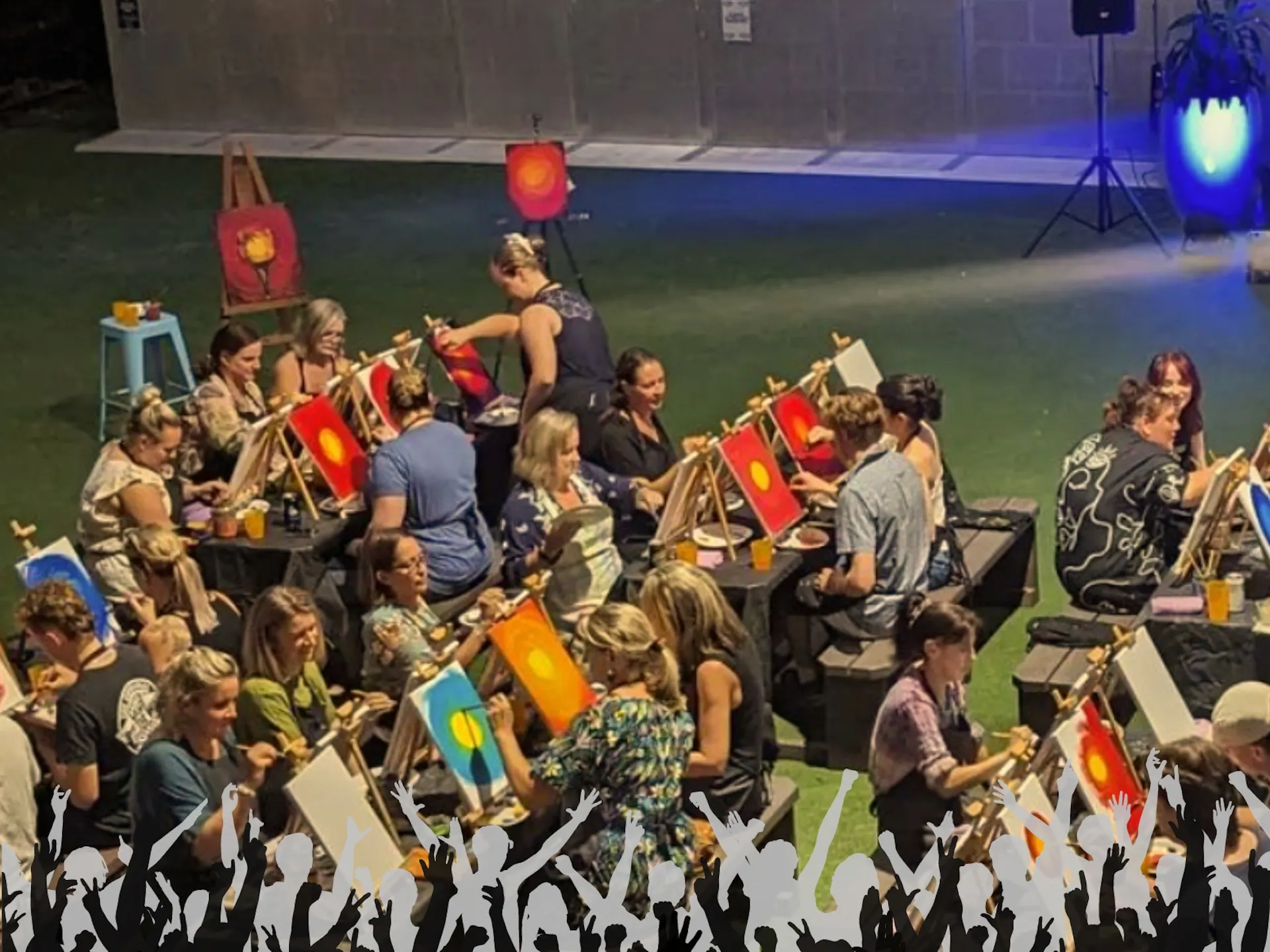 A photo taken from above showing people sitting at tables painting and having fun.