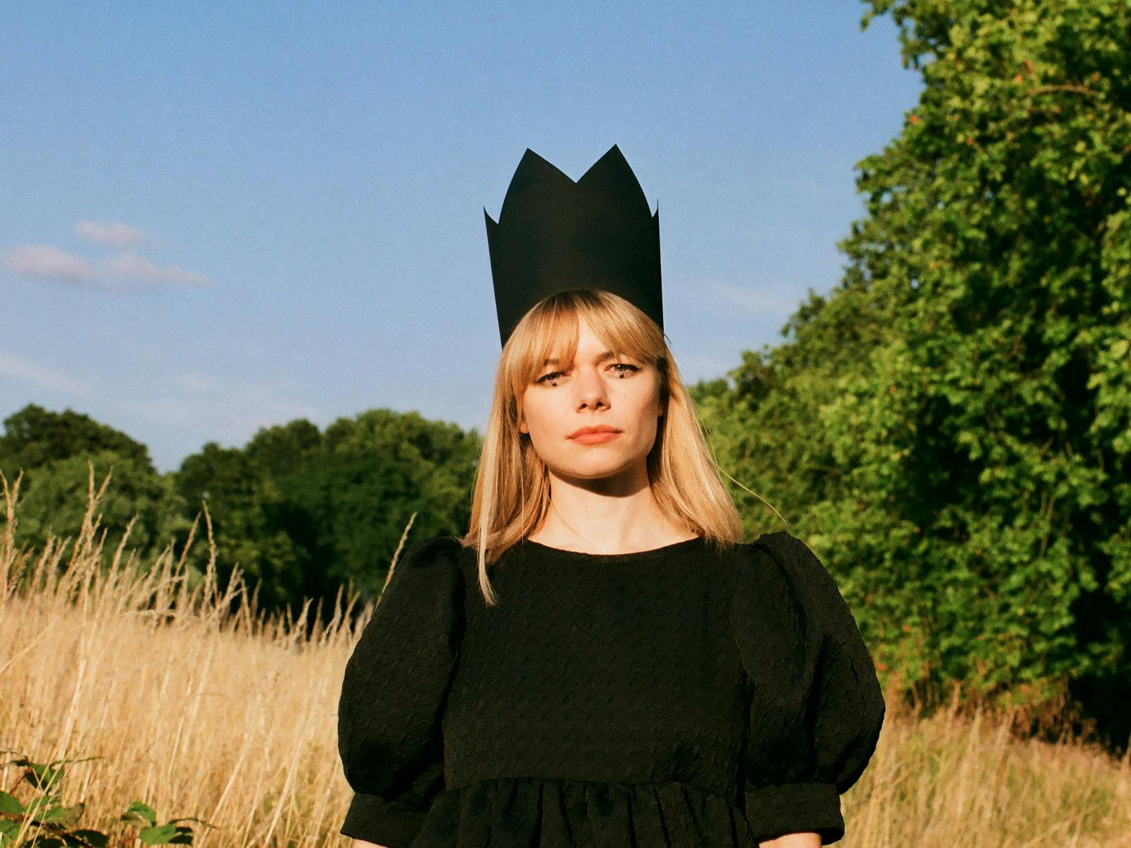 戴著黑色王冠的 Chloe Foy 在田野裡