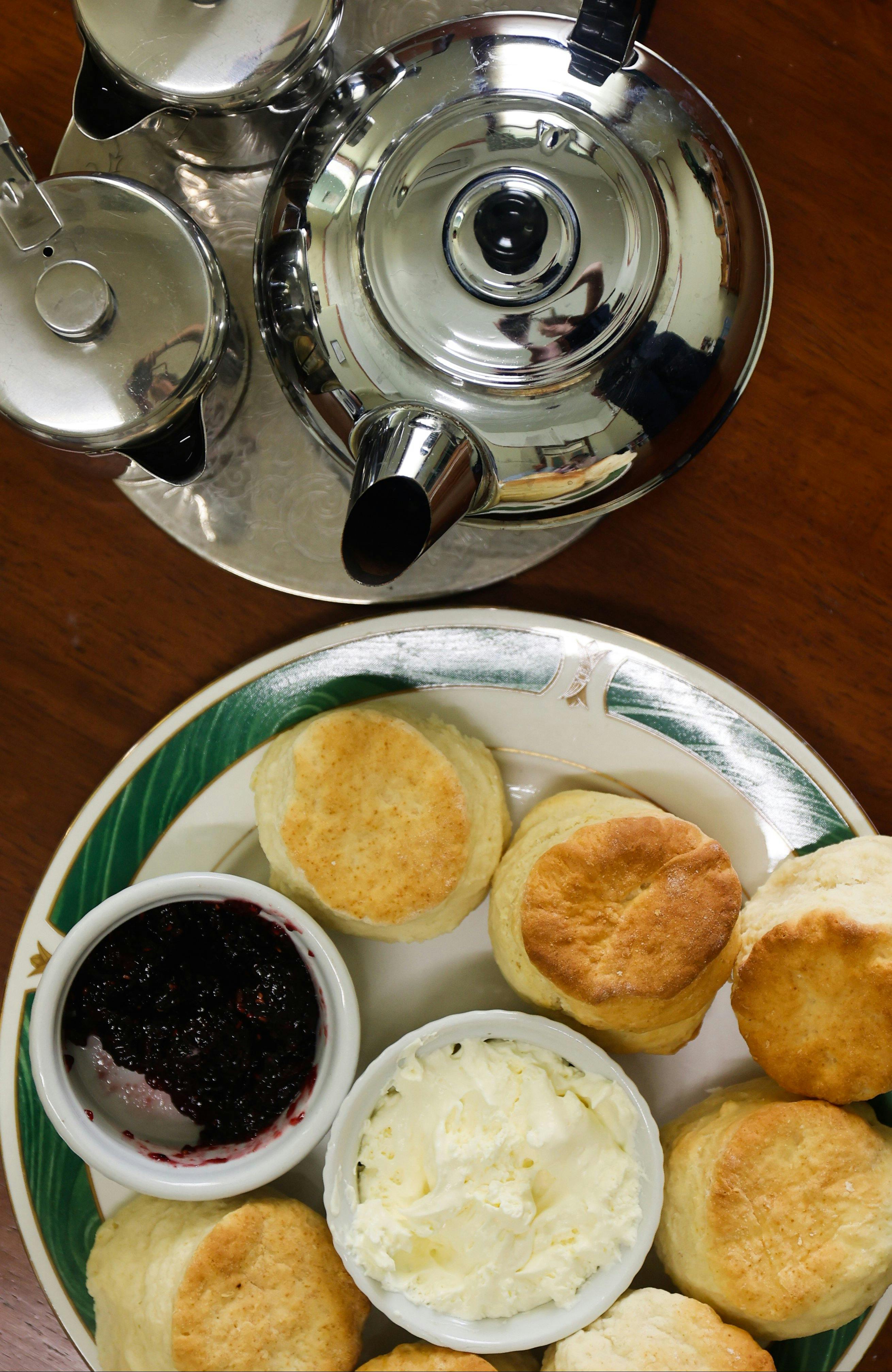 스콘 잼 크림 접시 옆에 찻주전자가 있습니다.