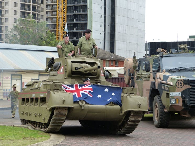 Museum's Matilda Tank named ACE drives past a contemporary Regimental Bushmaster in Lancer Barracks