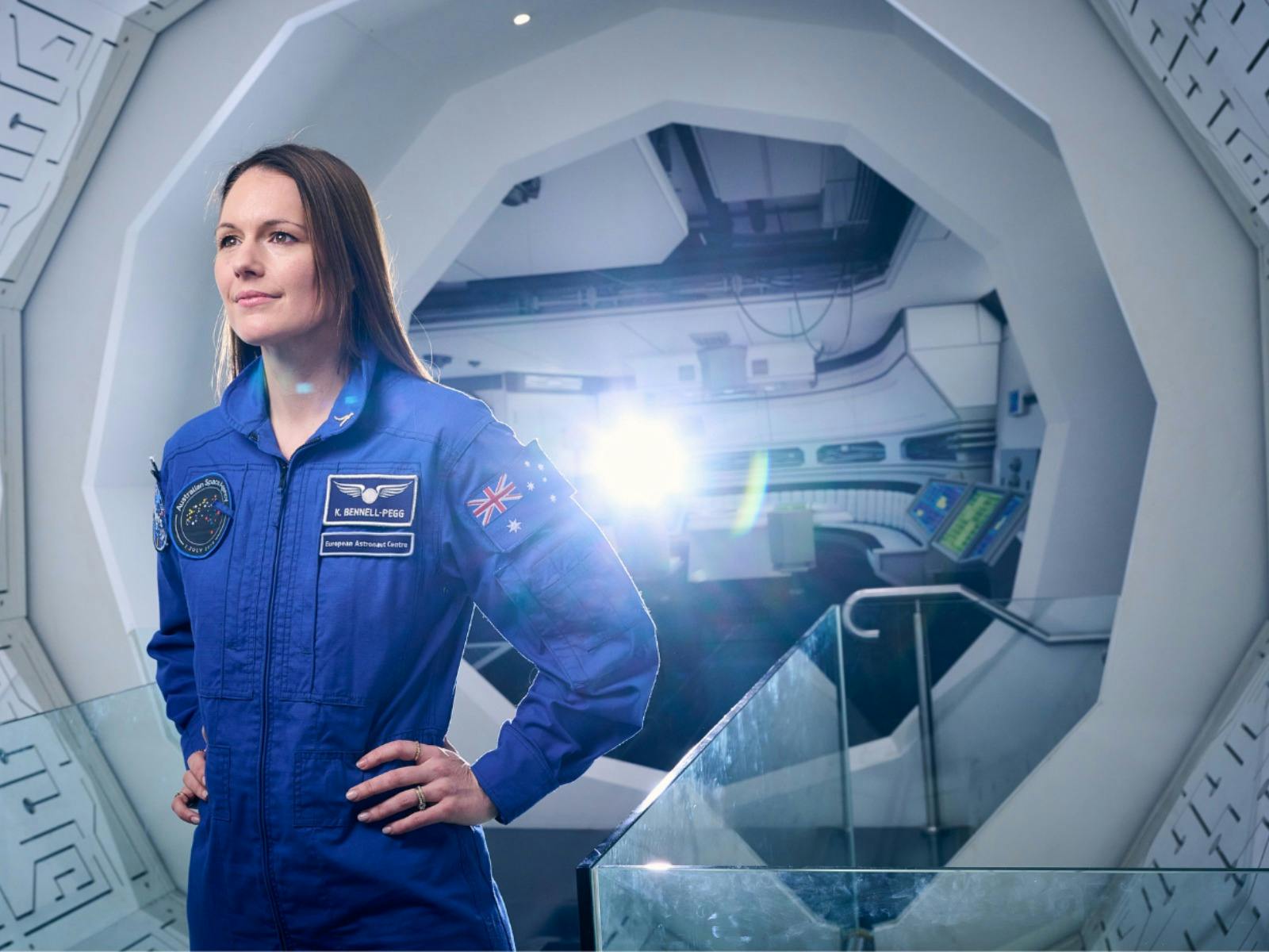 A woman at a space station wearing a blue astronaut uniform