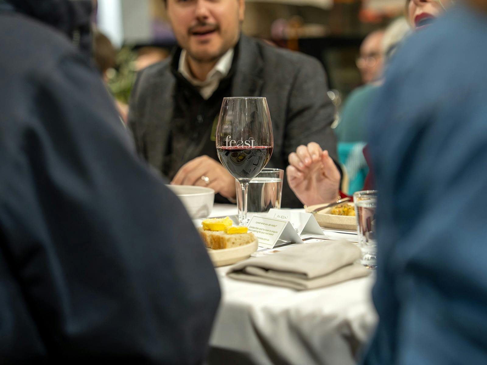 Guests sharing conversation with a glass of Barossa red in the foreground.