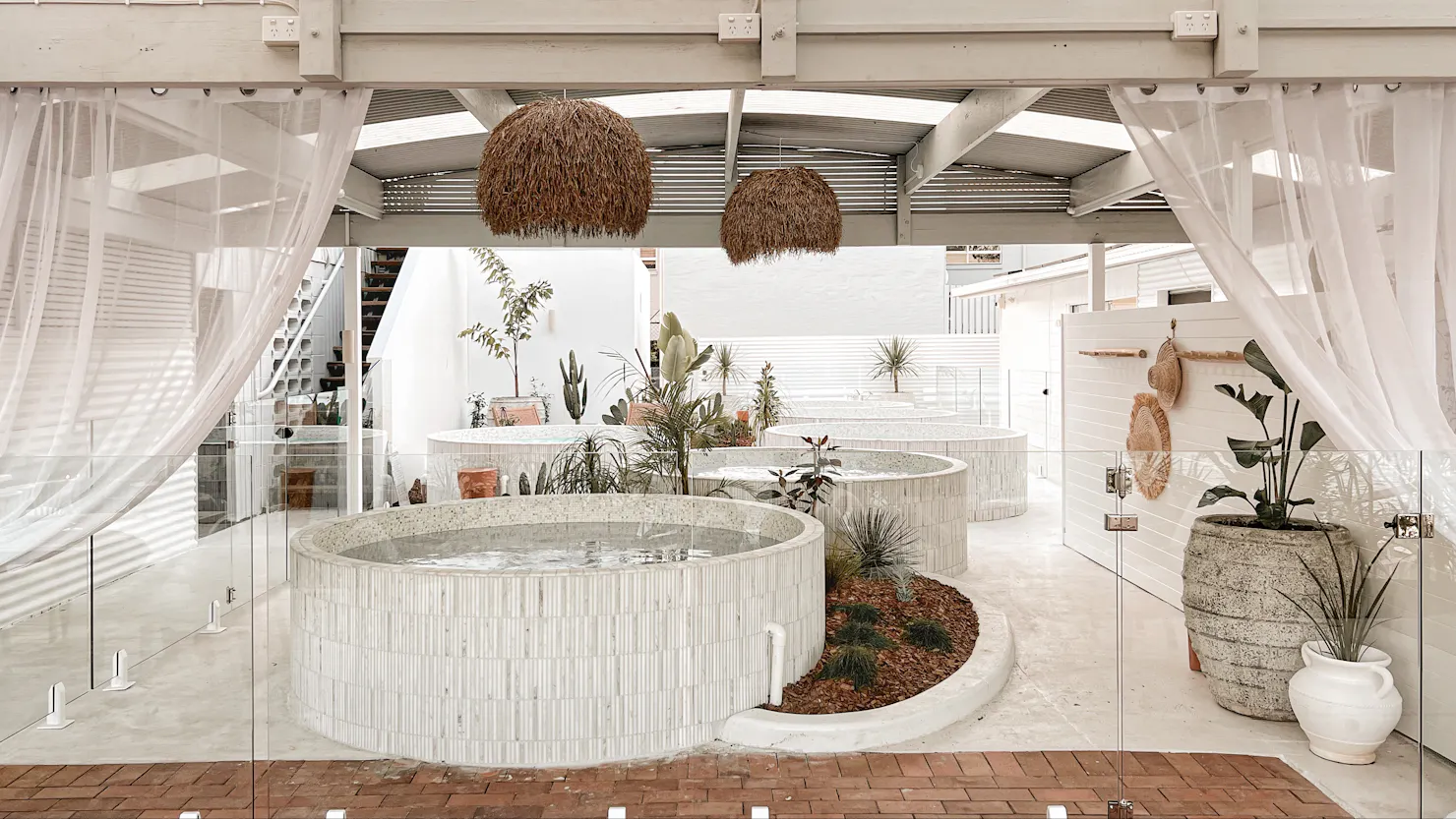 Mediterranean bathhouse with 6 round marble pools, ancient pots, sheer white breezy curtains, plants