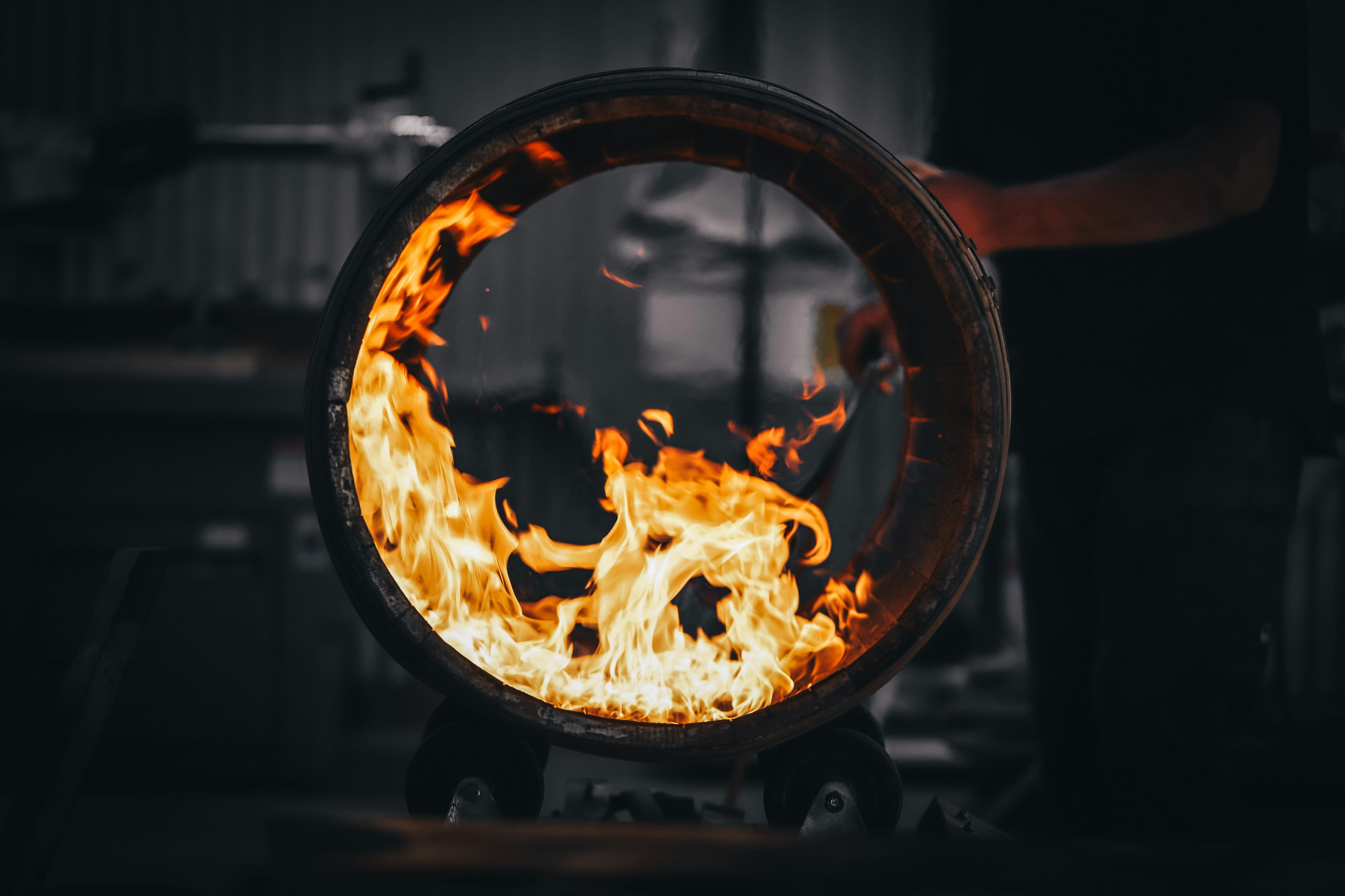 A barrel getting charred with a flame torch. The flames are swirling inside the barrel.