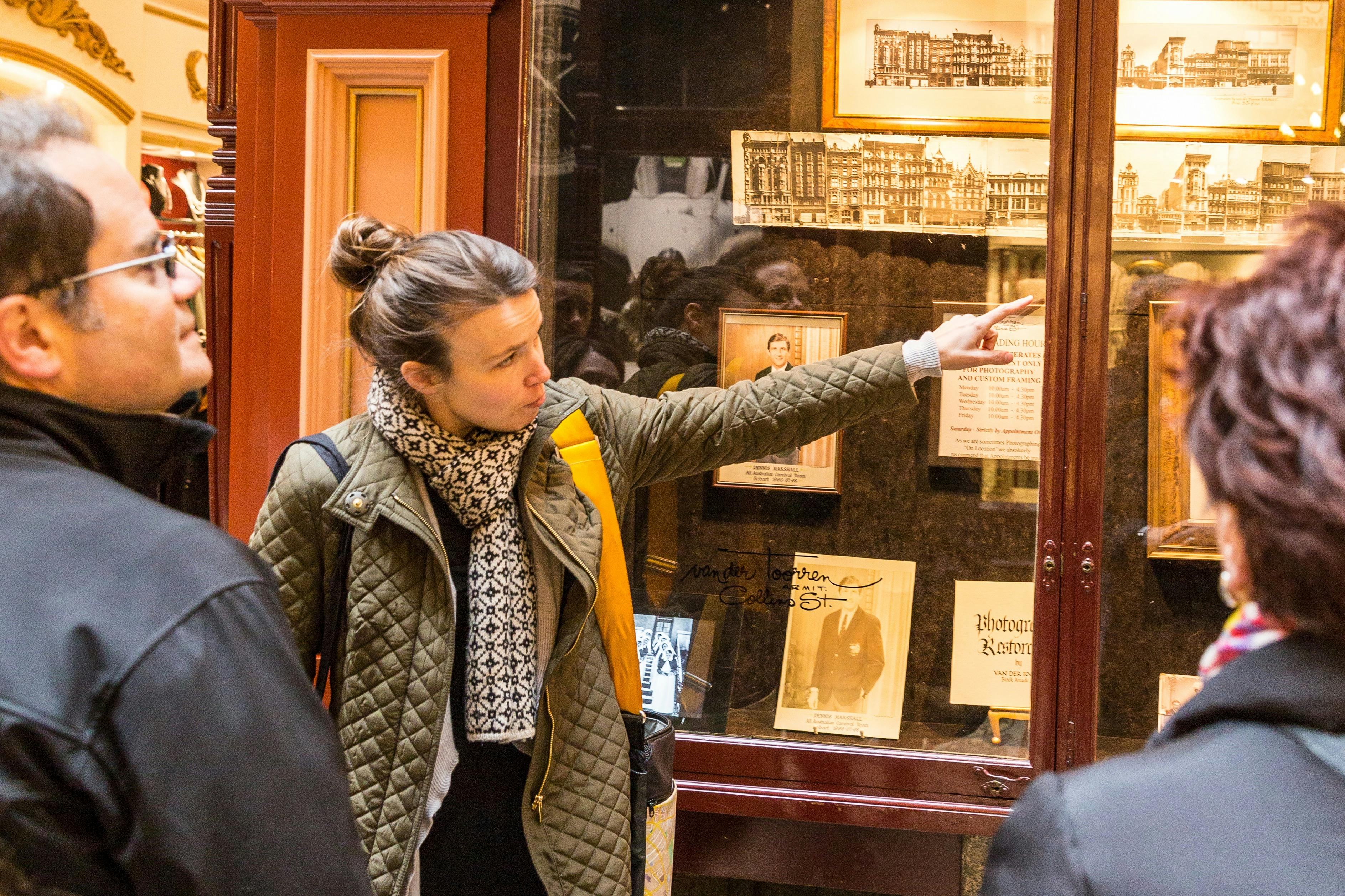 Woman stands pointing to historical photos, as she shares with another person, They are in an arcade