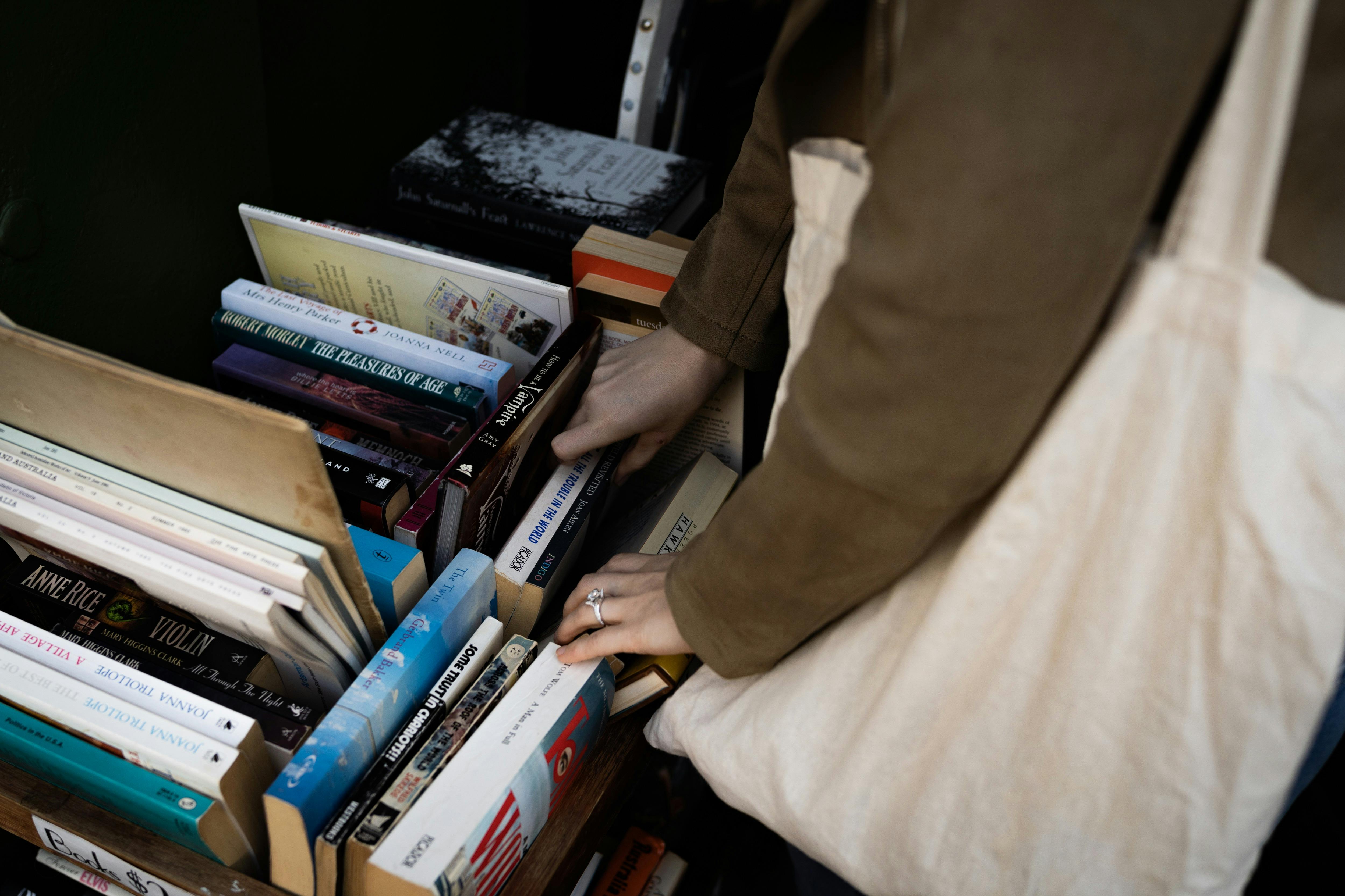A person holding a tote bag peruses a book stall.