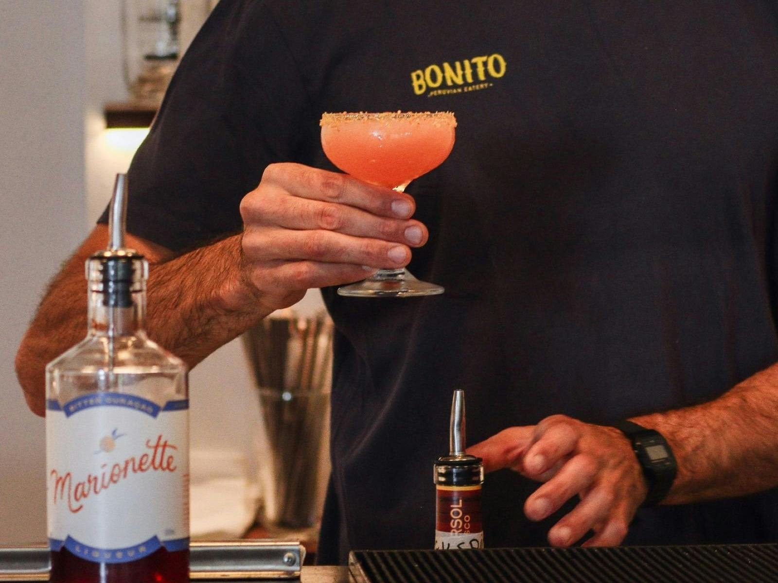 man behind bar making cocktail