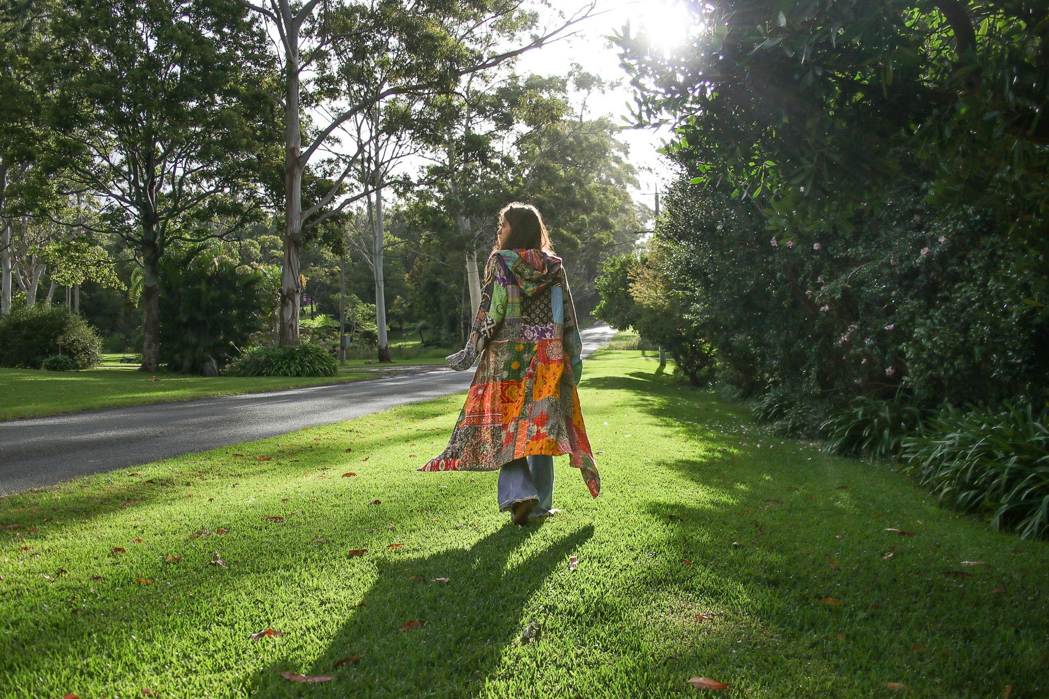 woman walking down road wearing patchwork coat