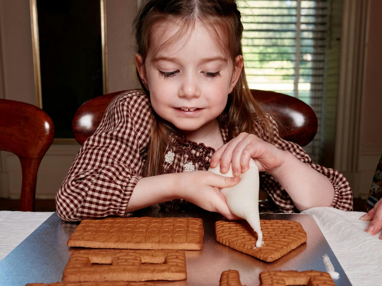 Gingerbread making class at Como House with girl piping icing on gingerbread house
