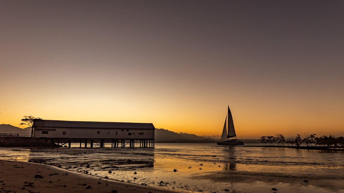 The sun setting behind the Sugar Wharf with a sailing boat in the scene