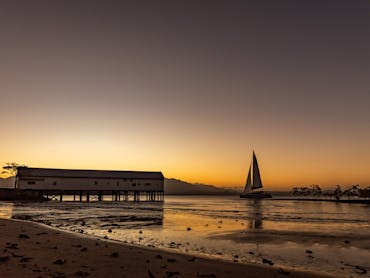The sun setting behind the Sugar Wharf with a sailing boat in the scene