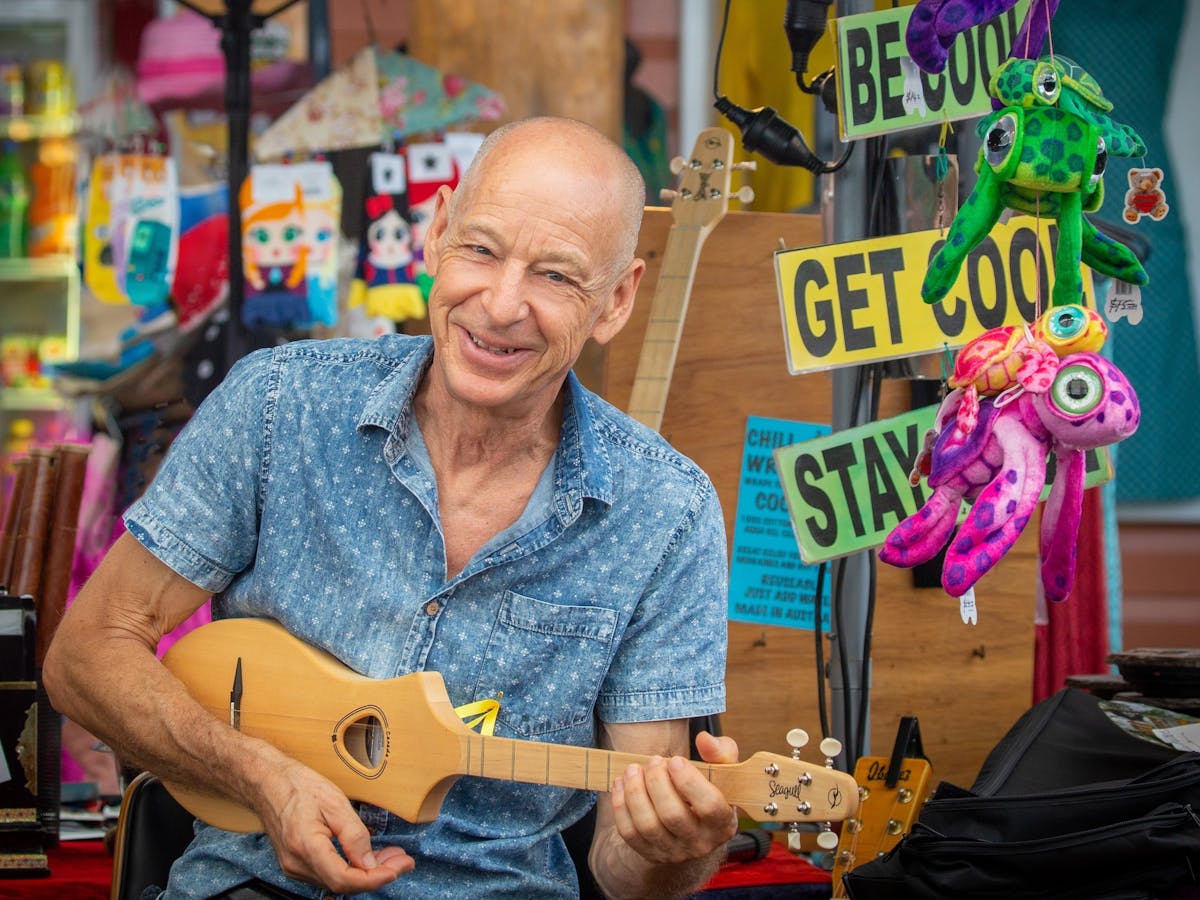 A man holds a ukelele outside his market stall in Kuranda, Tropical North Queensland.