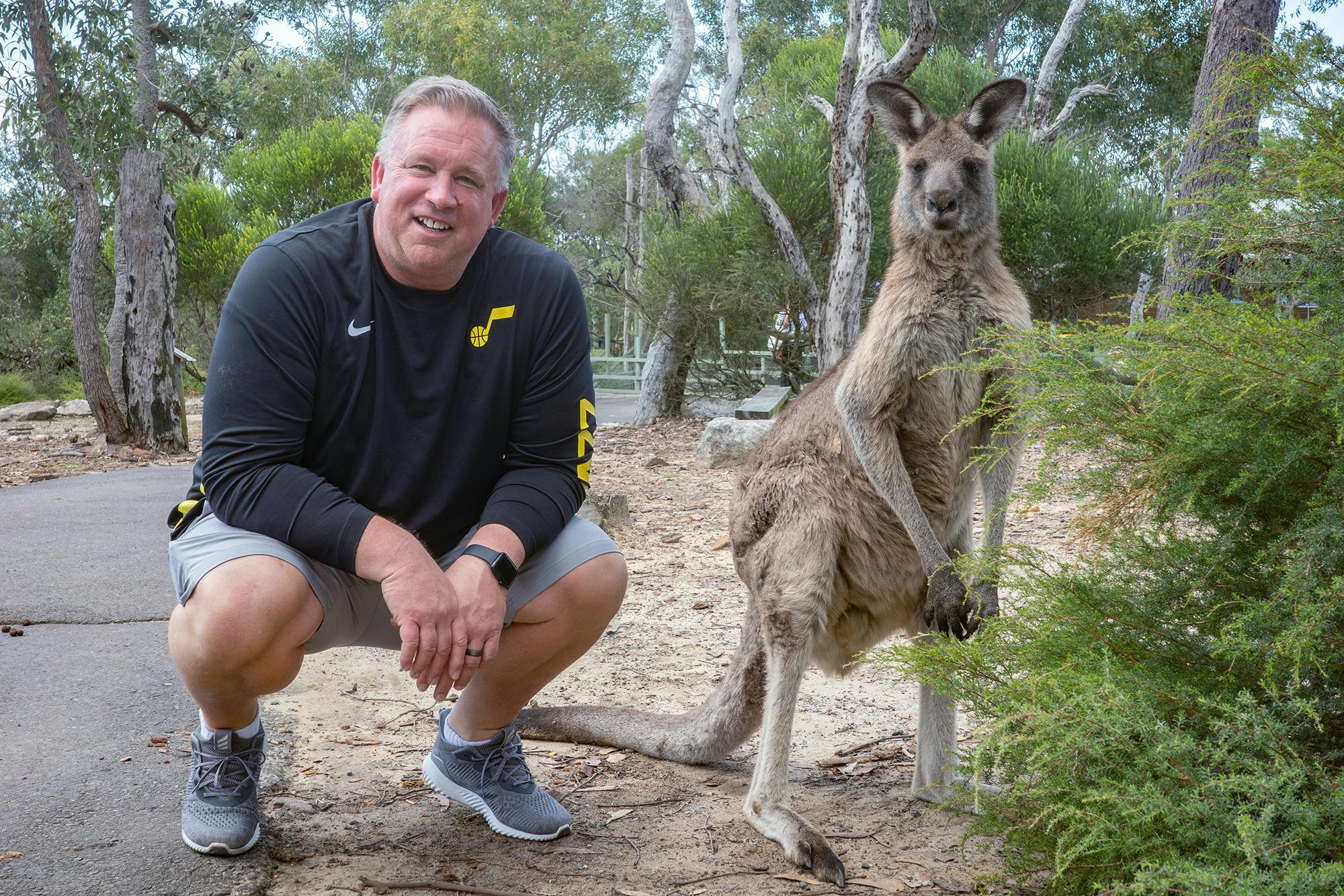 Man squatting next to kangaroo