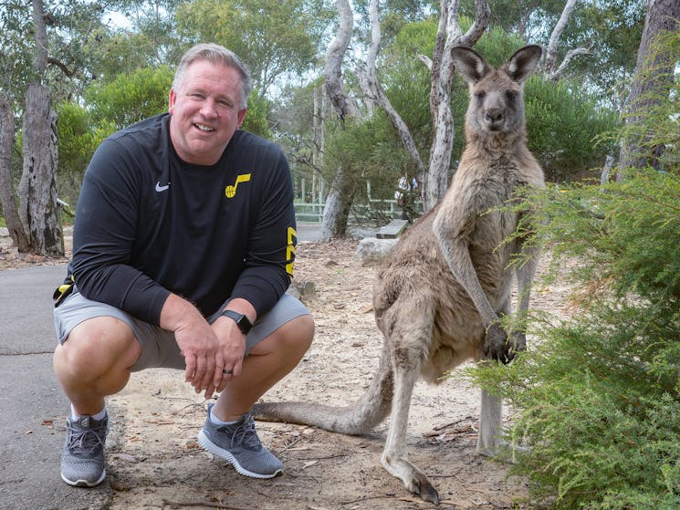 Man squatting next to kangaroo