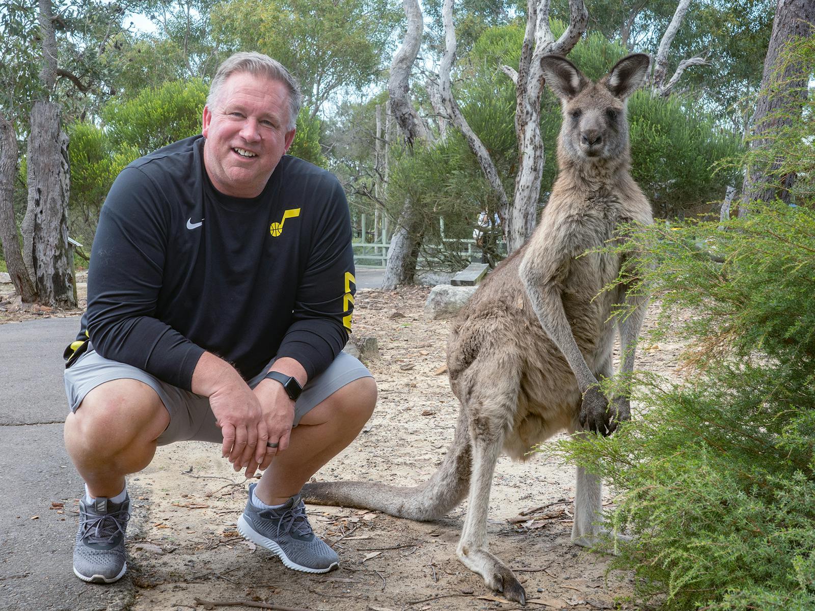 Man squatting next to kangaroo