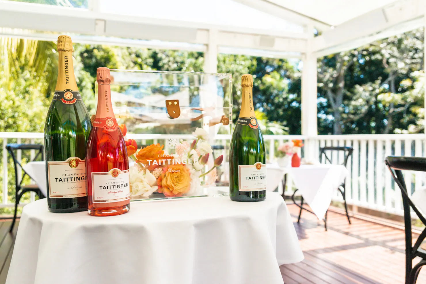 Three big bottles of Taittinger champagne set on a table on a verandah