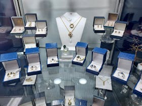 Sapphire Jewellery displayed on glass shelf in cabinet.