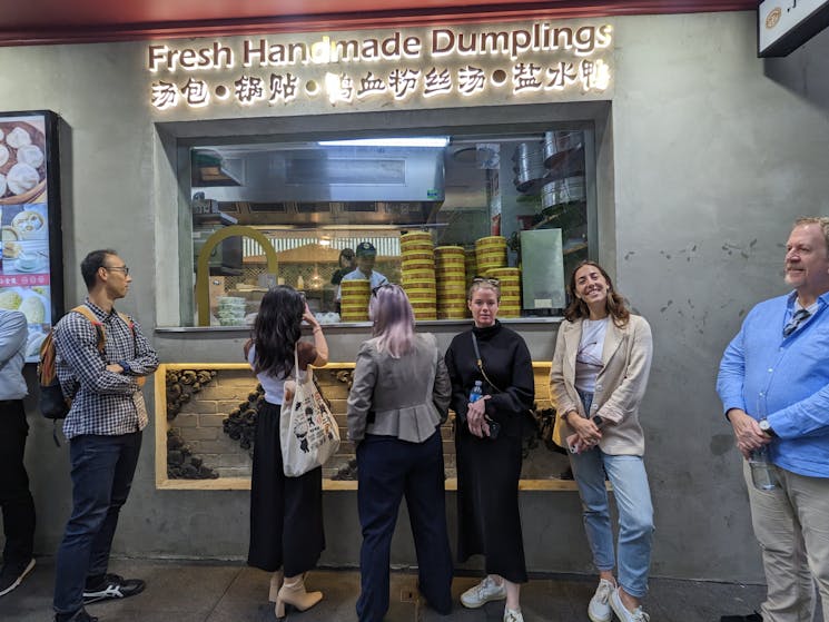 Restaurant shopfront with customers lined up to be seated