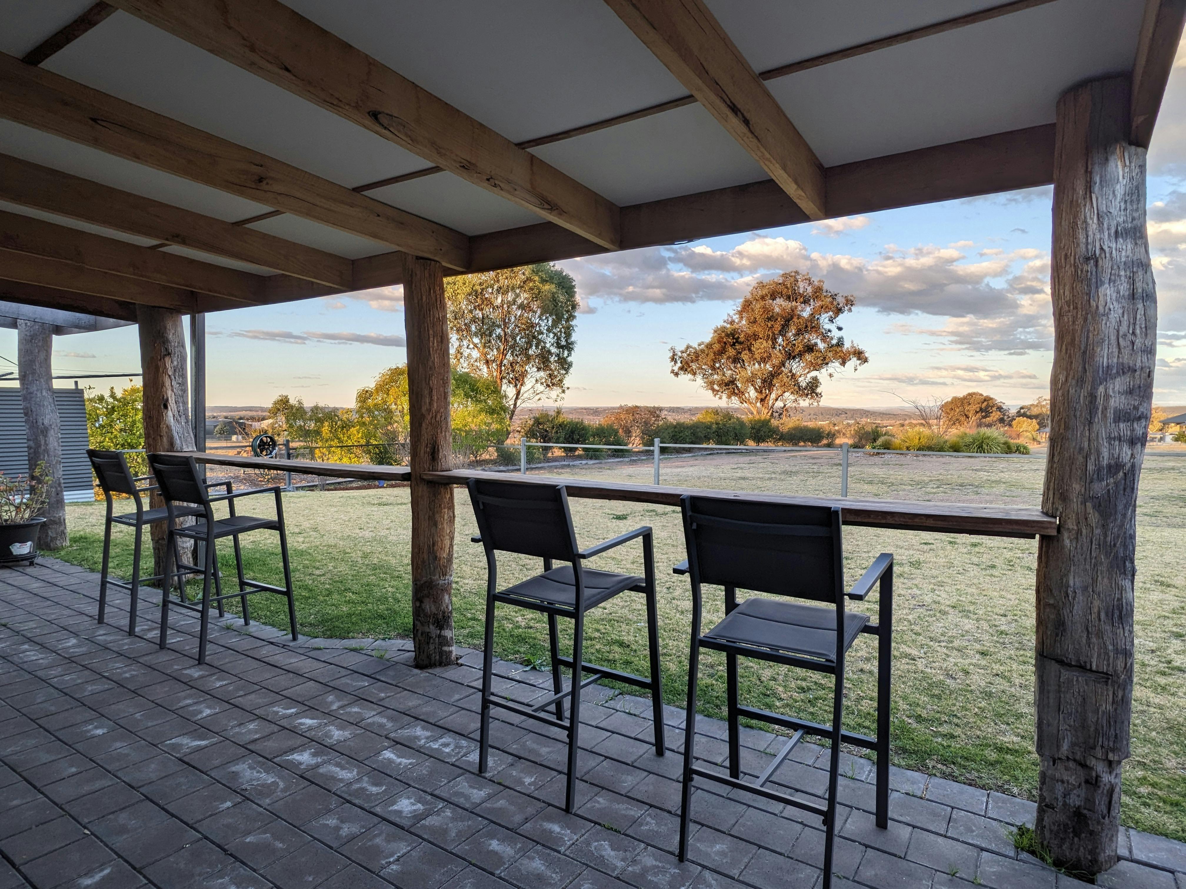 Four chairs at a wooden bench with views over the lawn and hills in the background