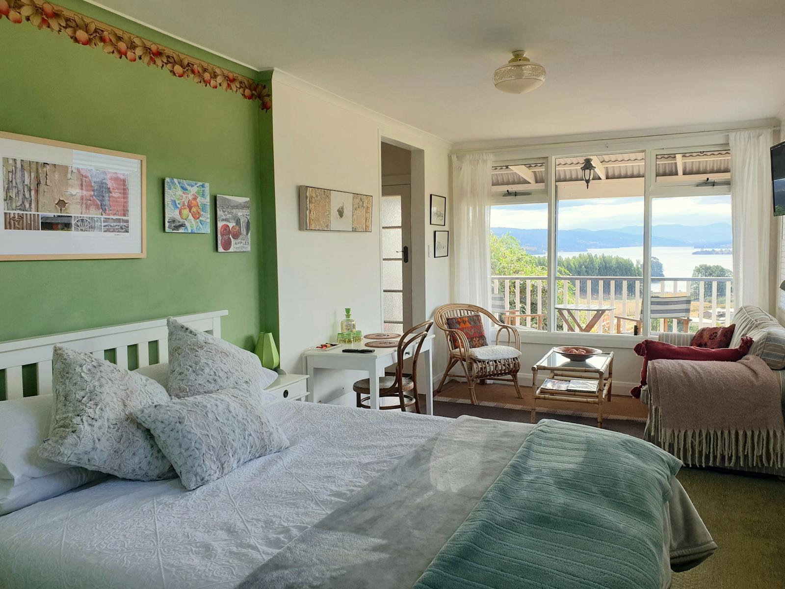 Queen bed with water views through large window.