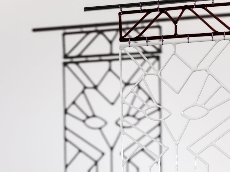 Intricately worked hanging of aa clear glass panel casting a shadow that looks like another image