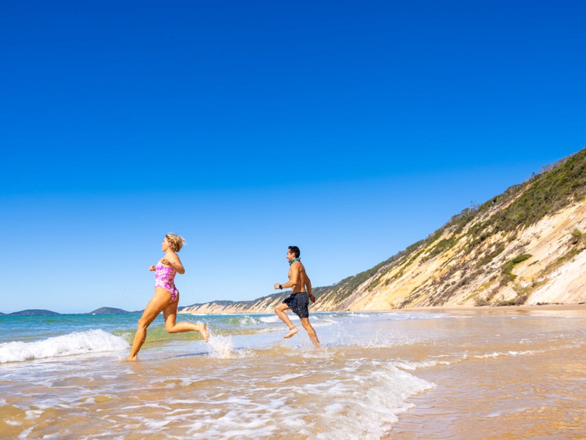 people running into the ocean at Rainbow Beach people running into the ocean at Rainbow Beach