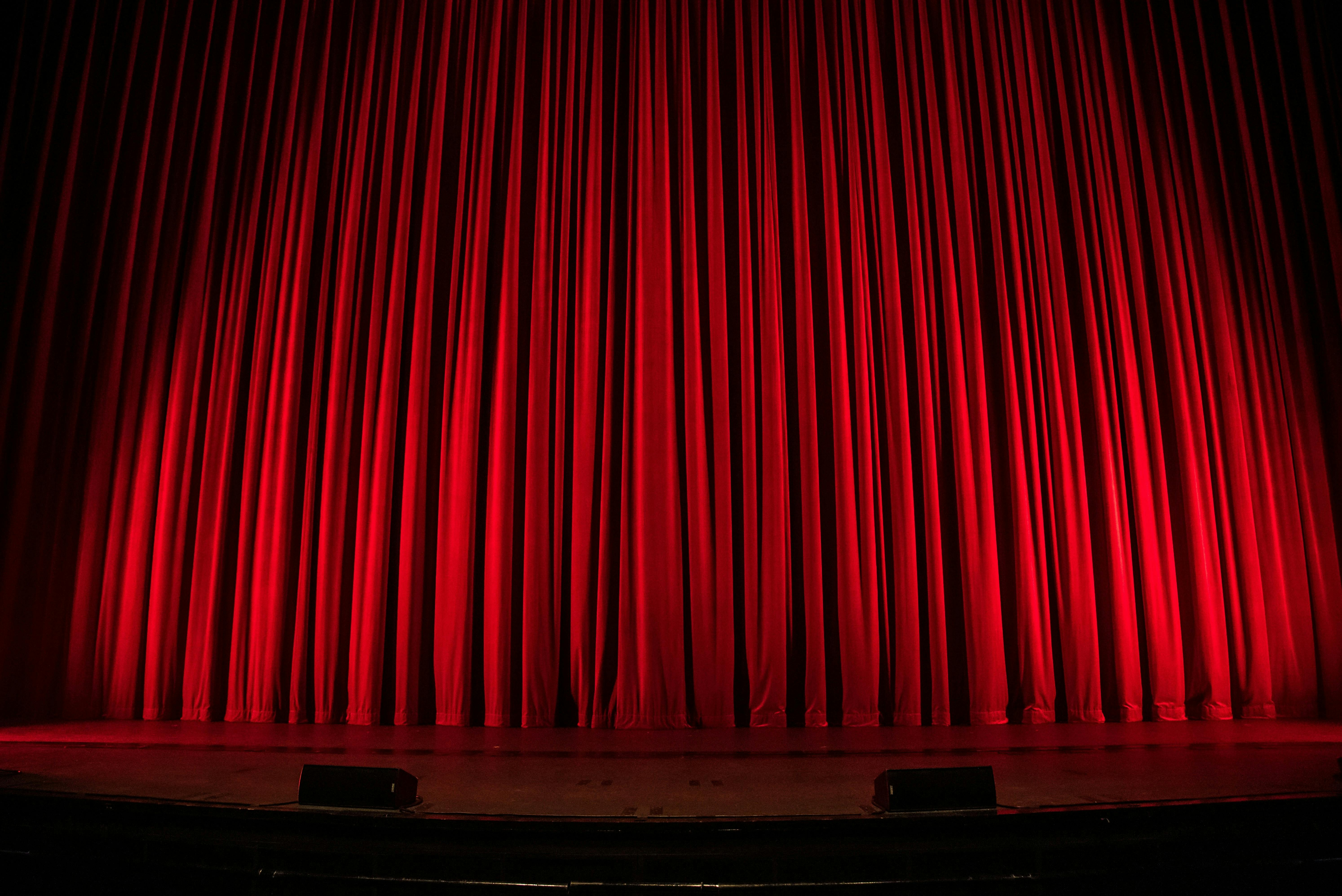 A red velvet curtain hides a performance stage