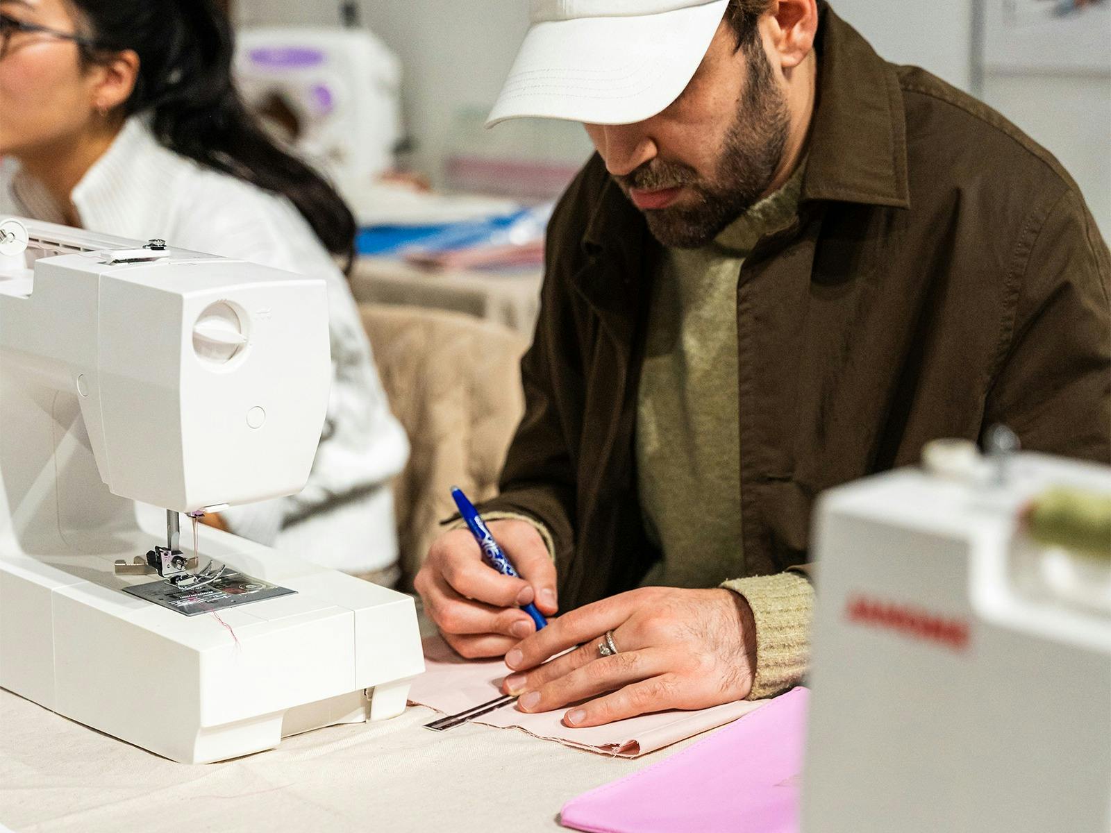 Sewing workshop Visitor marks fabric during a hands-on sewing workshop with sewing machines.