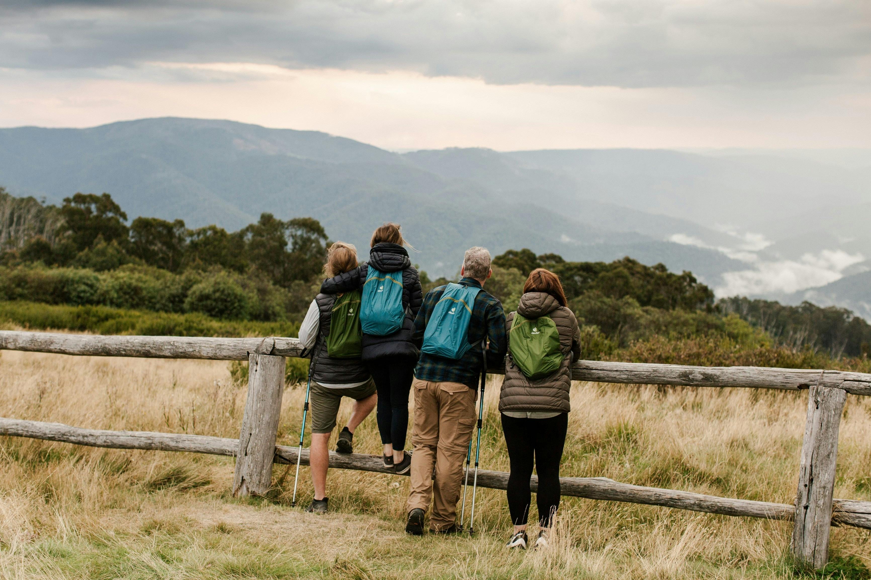 People leaning against fence with mountain view in backdrop