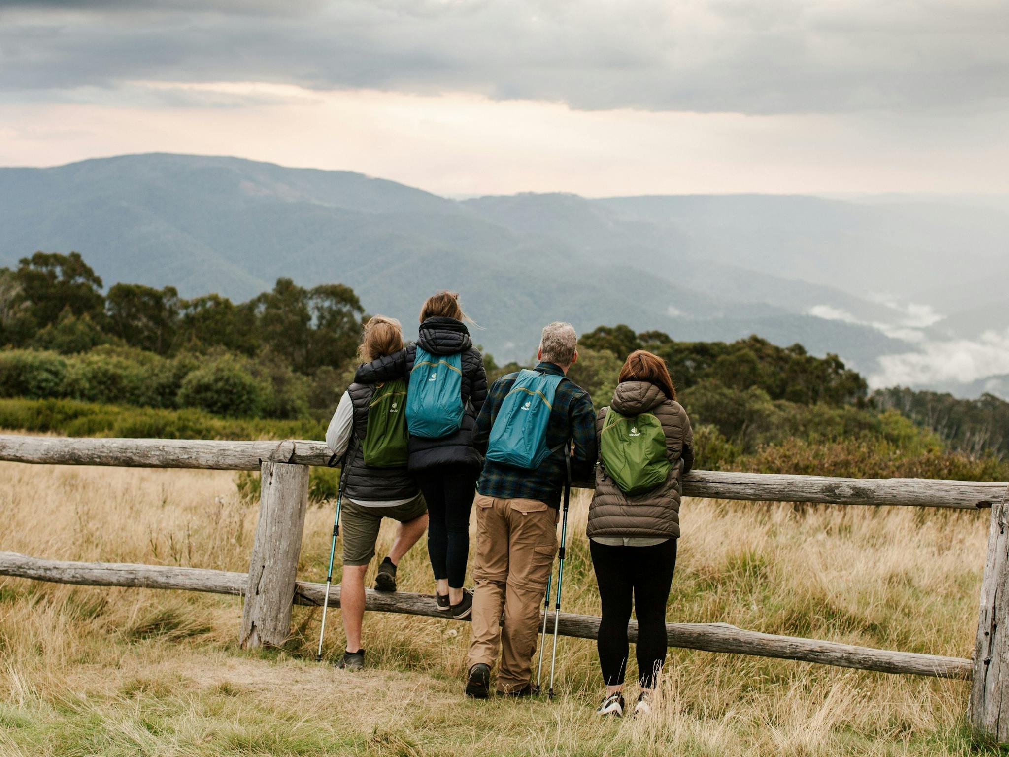 People leaning against fence with mountain view in backdrop
