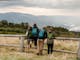 People leaning against fence with mountain view in backdrop