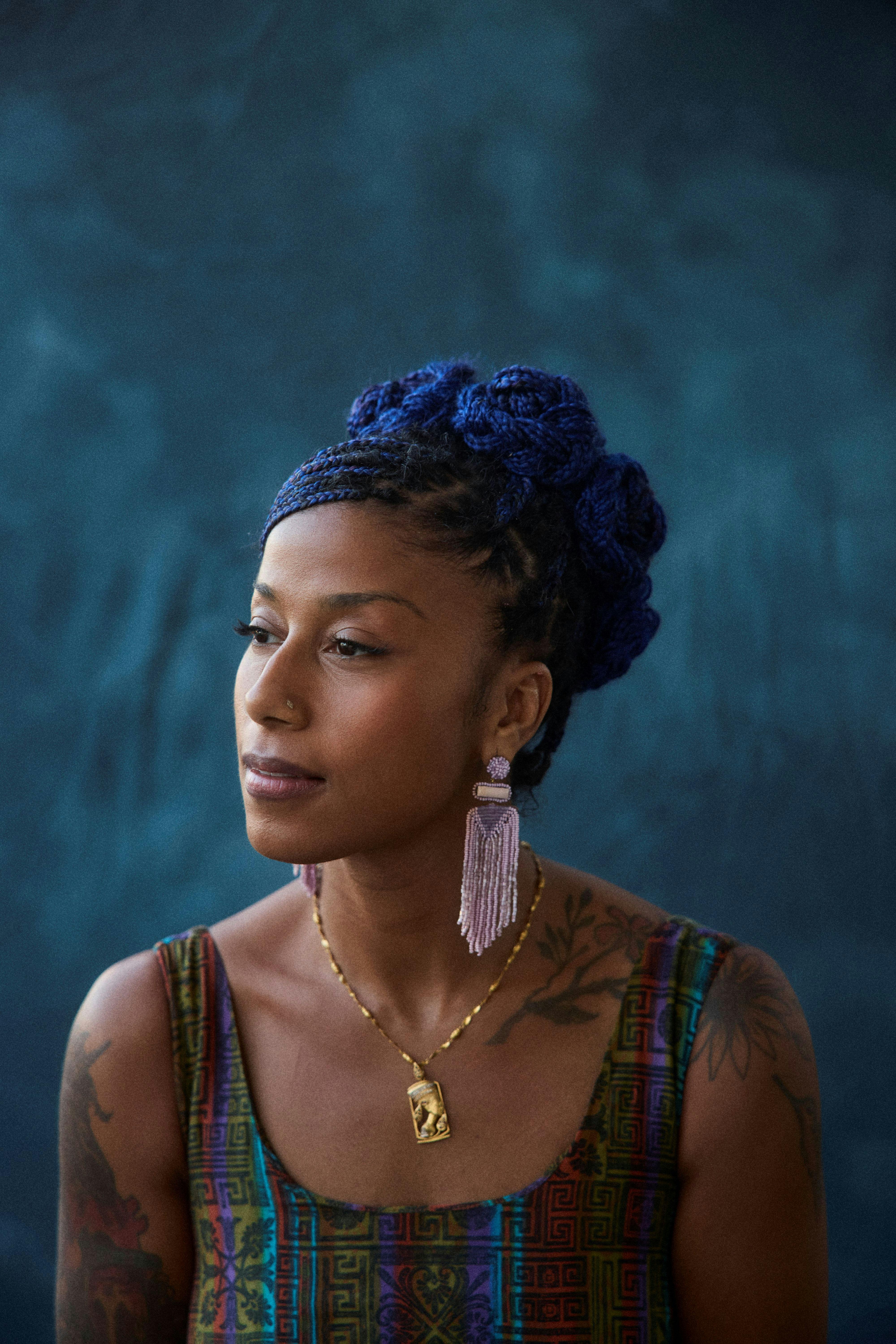 Portrait image of a woman sitting against a blue background.