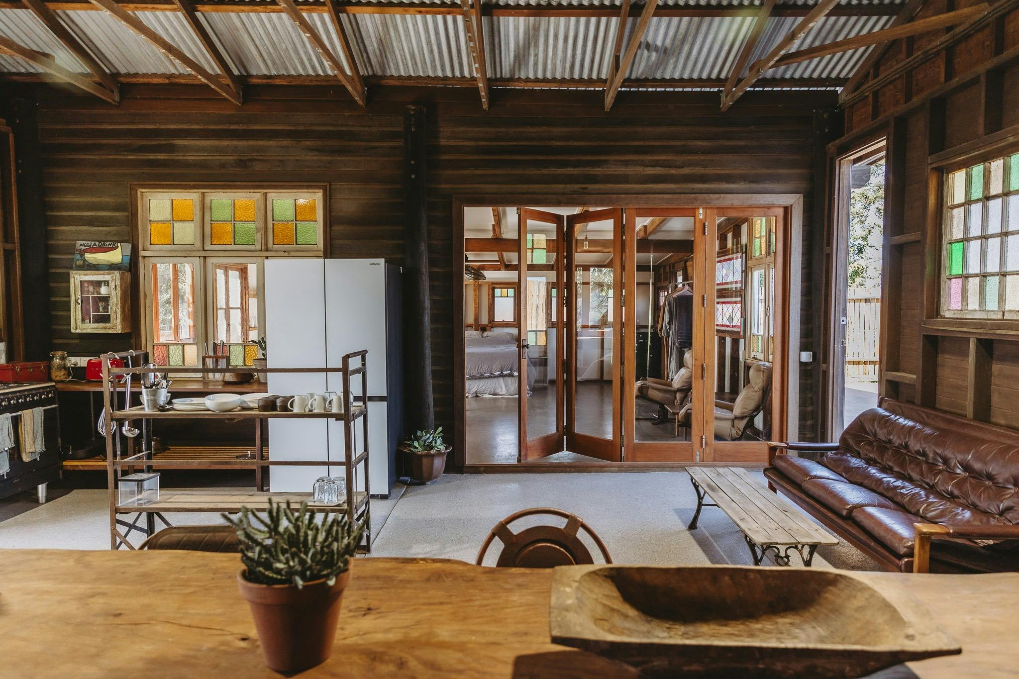 An open style kitchen in a timber farm cottage with french folding glass doors to a bedroom