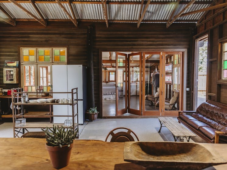 An open style kitchen in a timber farm cottage with french folding glass doors to a bedroom