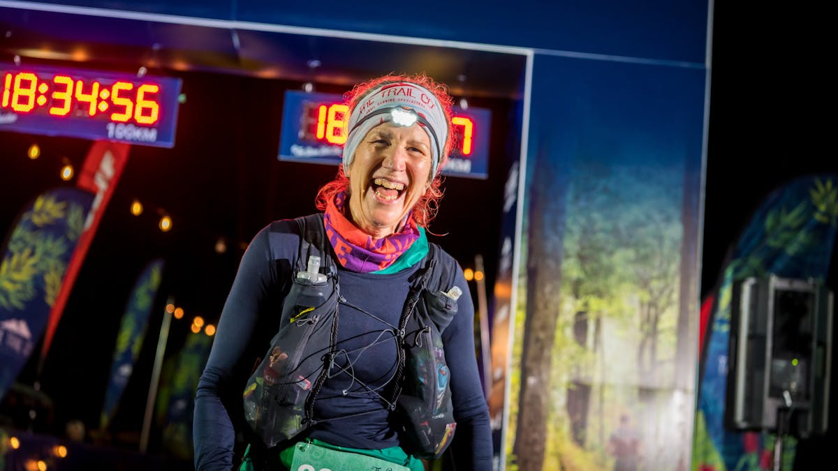 A runner smiles after crossing the 100km finish line