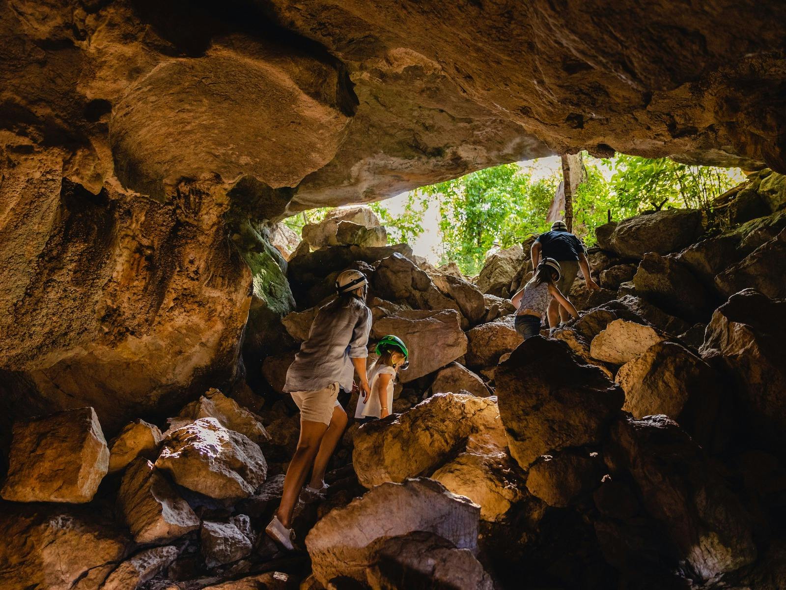 Family climbing the rocks to exit the cave Family climbing the rocks to exit the cave