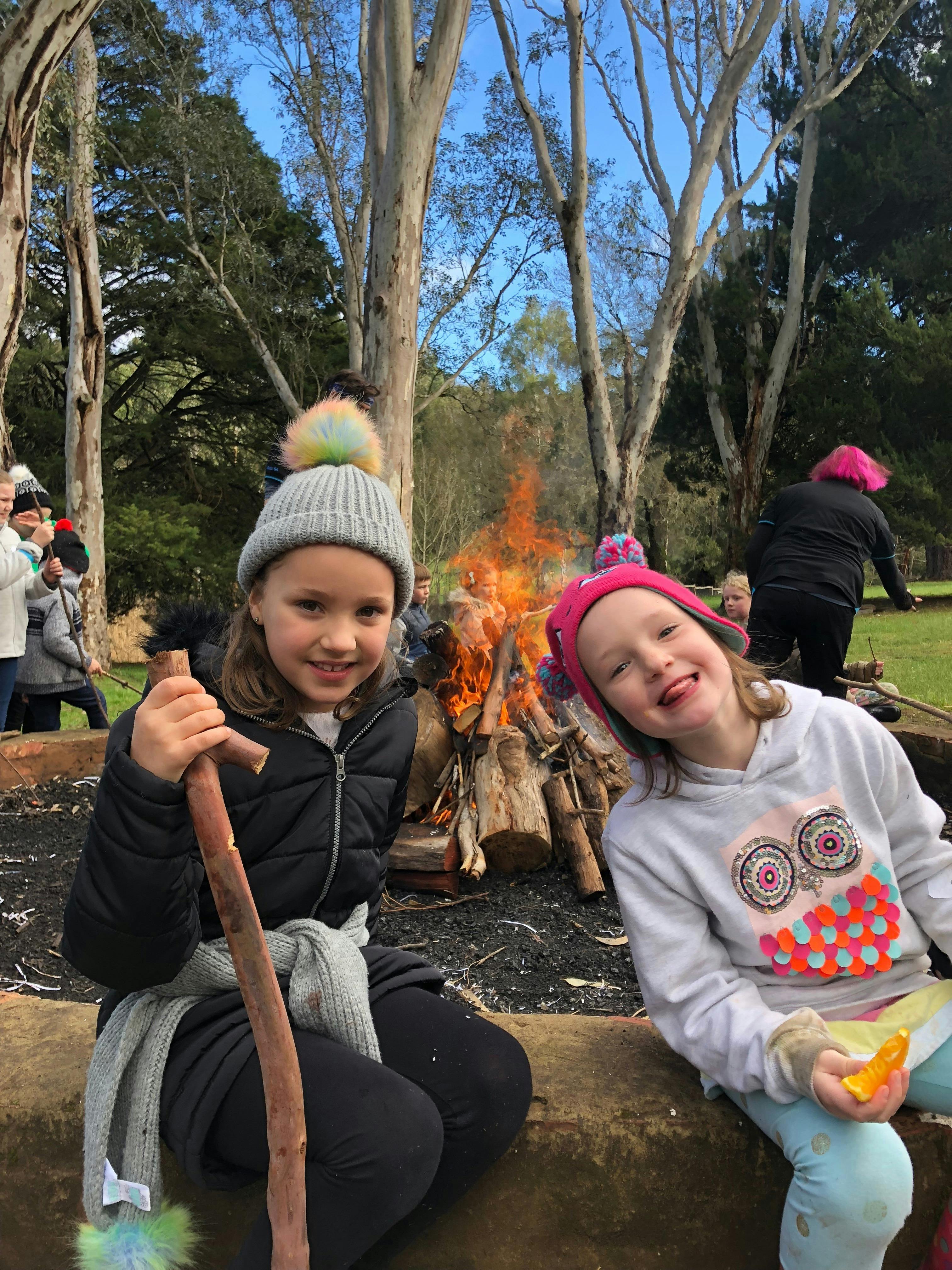 Two girls sitting in front of campfire