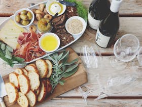 Overhead view of a local-produce filled grazing board with En Soleil and CJ wines, set on a rustic t
