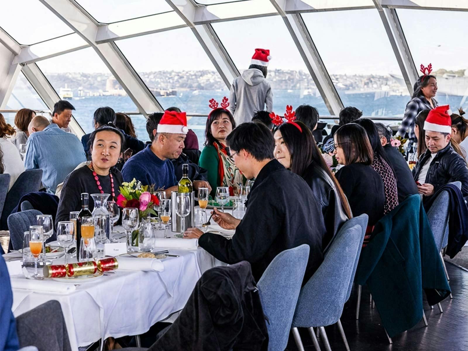 Guests dining aboard the Clearview Glass Boat in Sydney on Christmas Day, while wearing santa hats a
