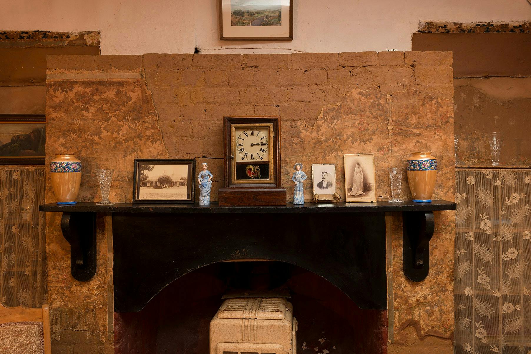 Fireplace in Mugga-Mugga cottage with historical photographs and objects